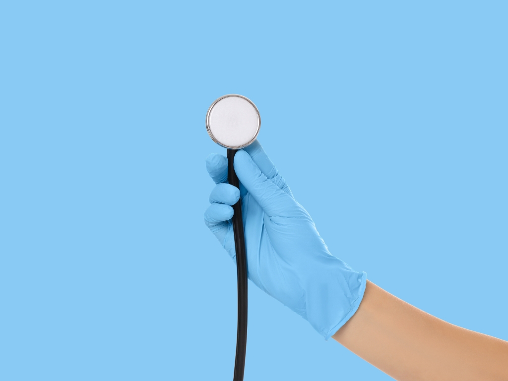 Close-up of a gloved hand holding a stethoscope against a blue background.